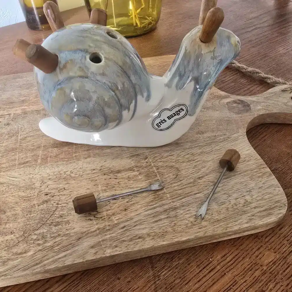 Escargot en grès vu de profil avec piques apéritifs.