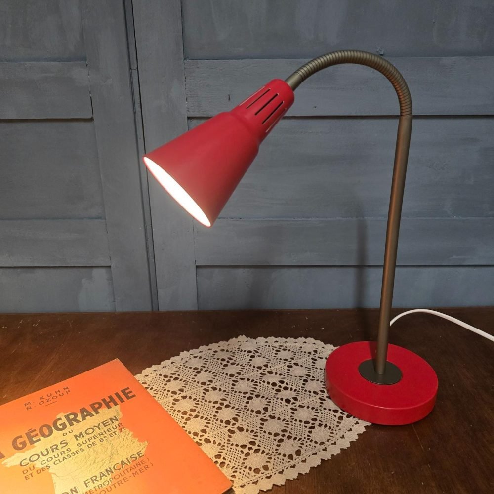 Lampe de bureau IKEA Kvart rouge, design Hagberg, allumée sur table en bois