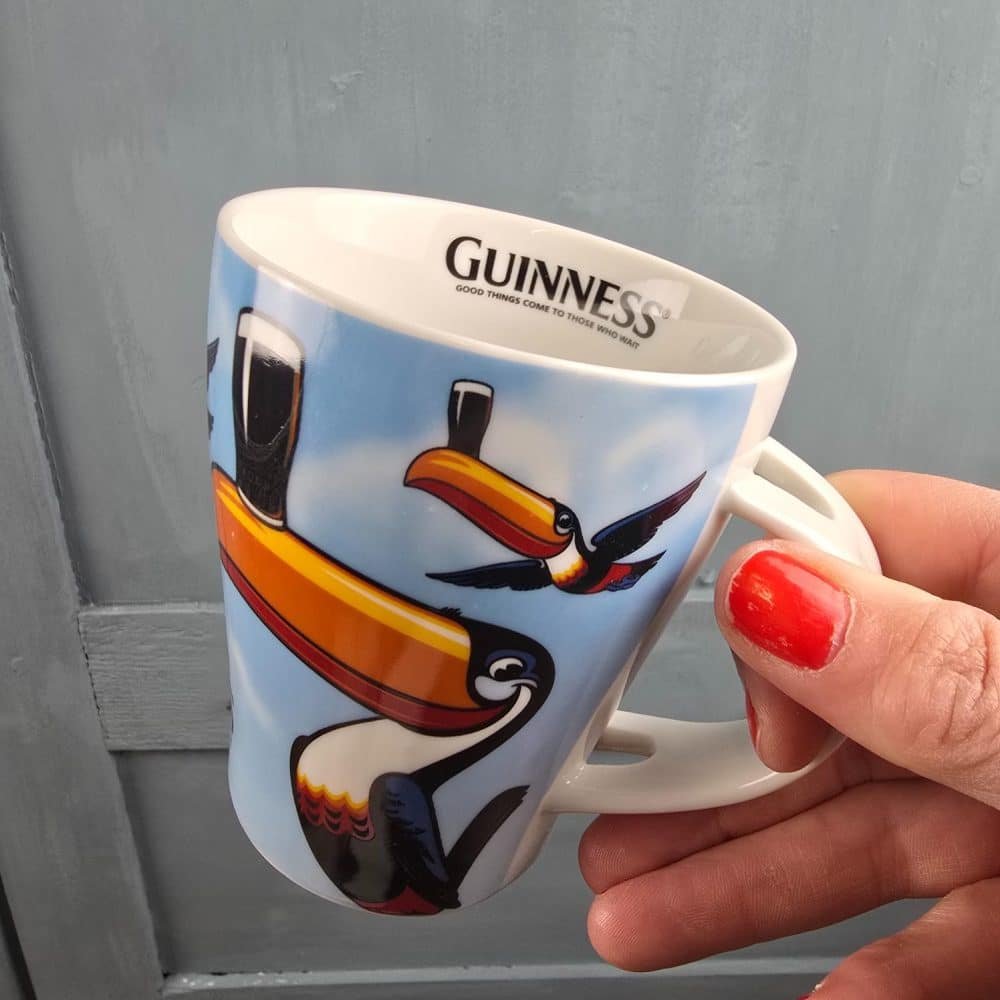 Mug Guinness décoré du toucan, tenue en main.