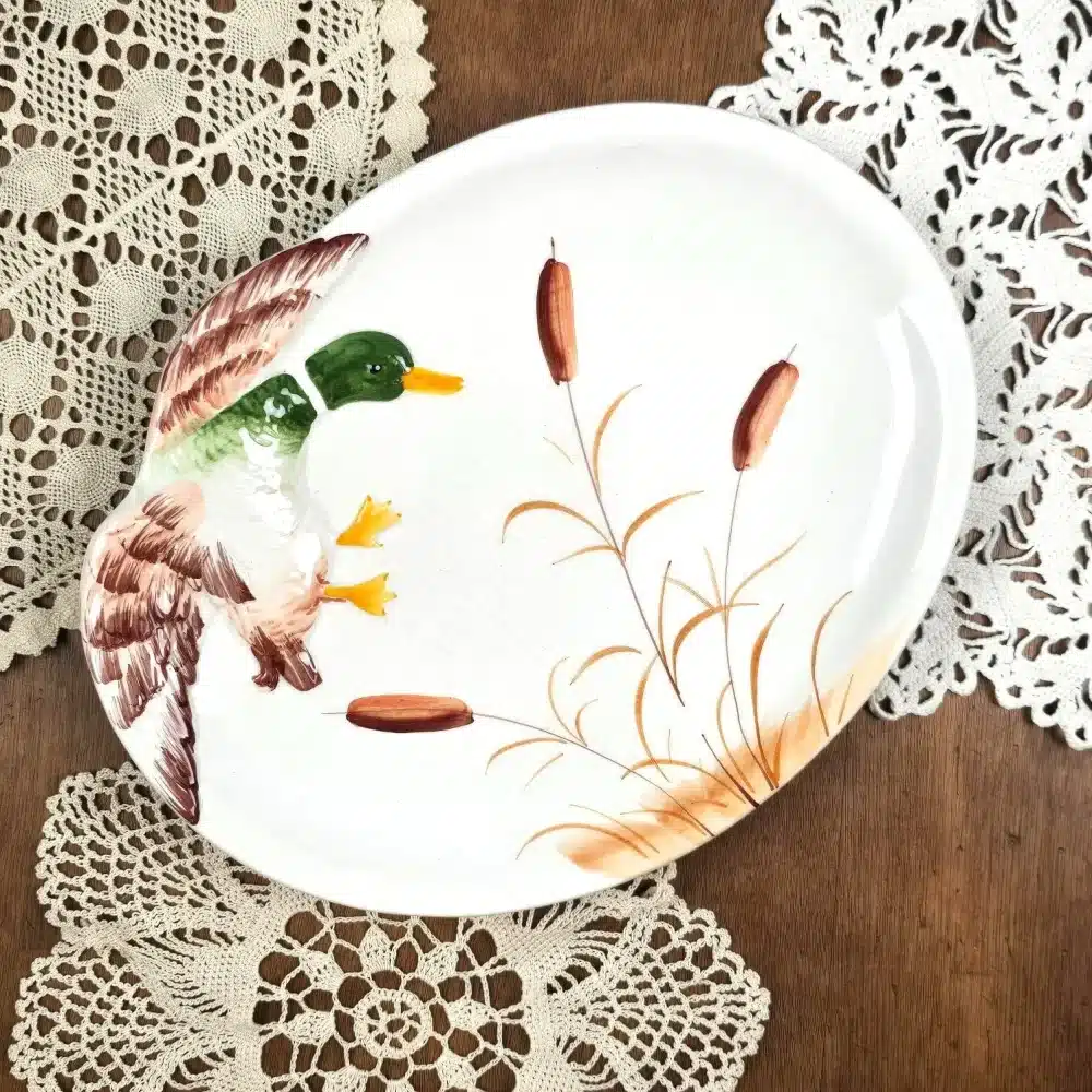 Plat vintage en céramique Made in Italy, décoré d’un canard en relief et de roseaux sur fond blanc.