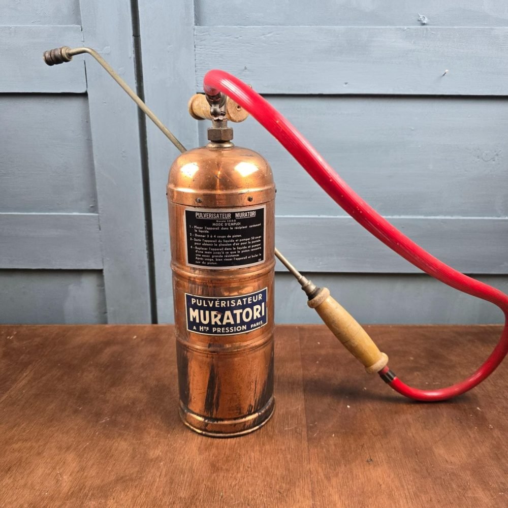 Pulvérisateur Muratori en cuivre avec lance et tuyau rouge, vue d’ensemble