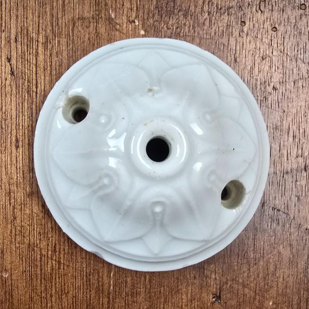 Rosace de plafond ancienne en porcelaine blanche vue de dessus sur table en bois