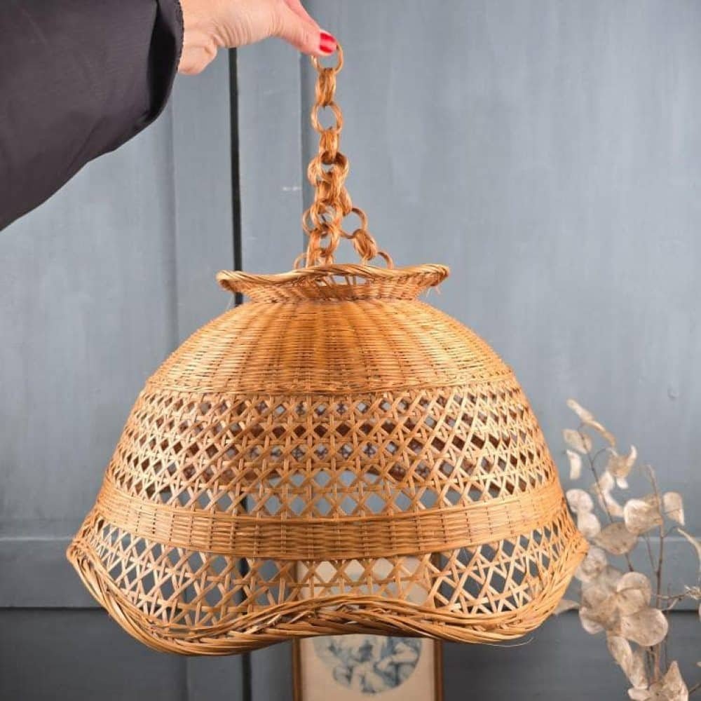 Suspension vintage en rotin tressé années 70, tenue à la main.