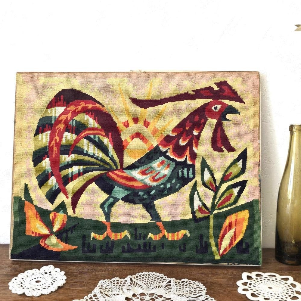 Tapisserie vintage brodée main représentant un coq coloré stylisé sur fond soleil levant